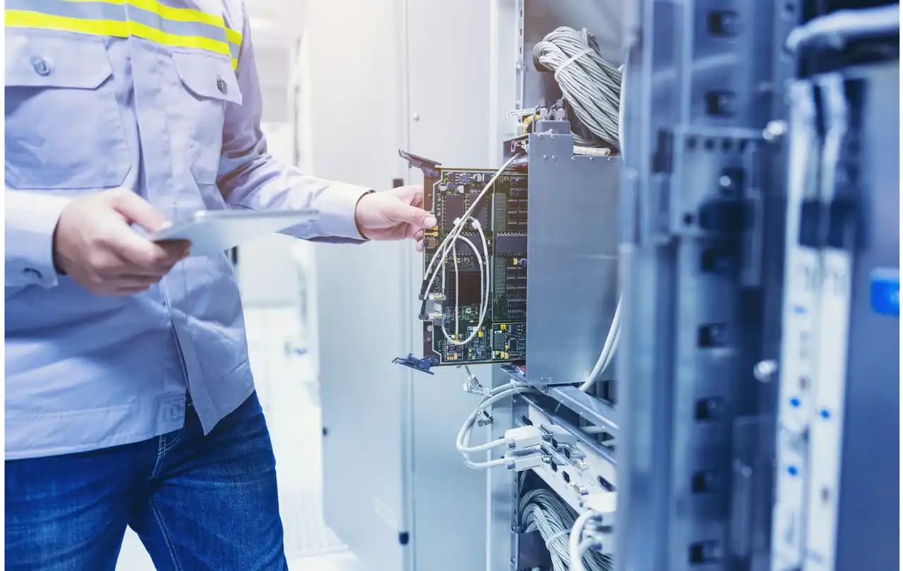 Technician connecting Ethernet cables in network equipment rack, illustrating structured cabling and how connectors impact maximum cable length in commercial networks