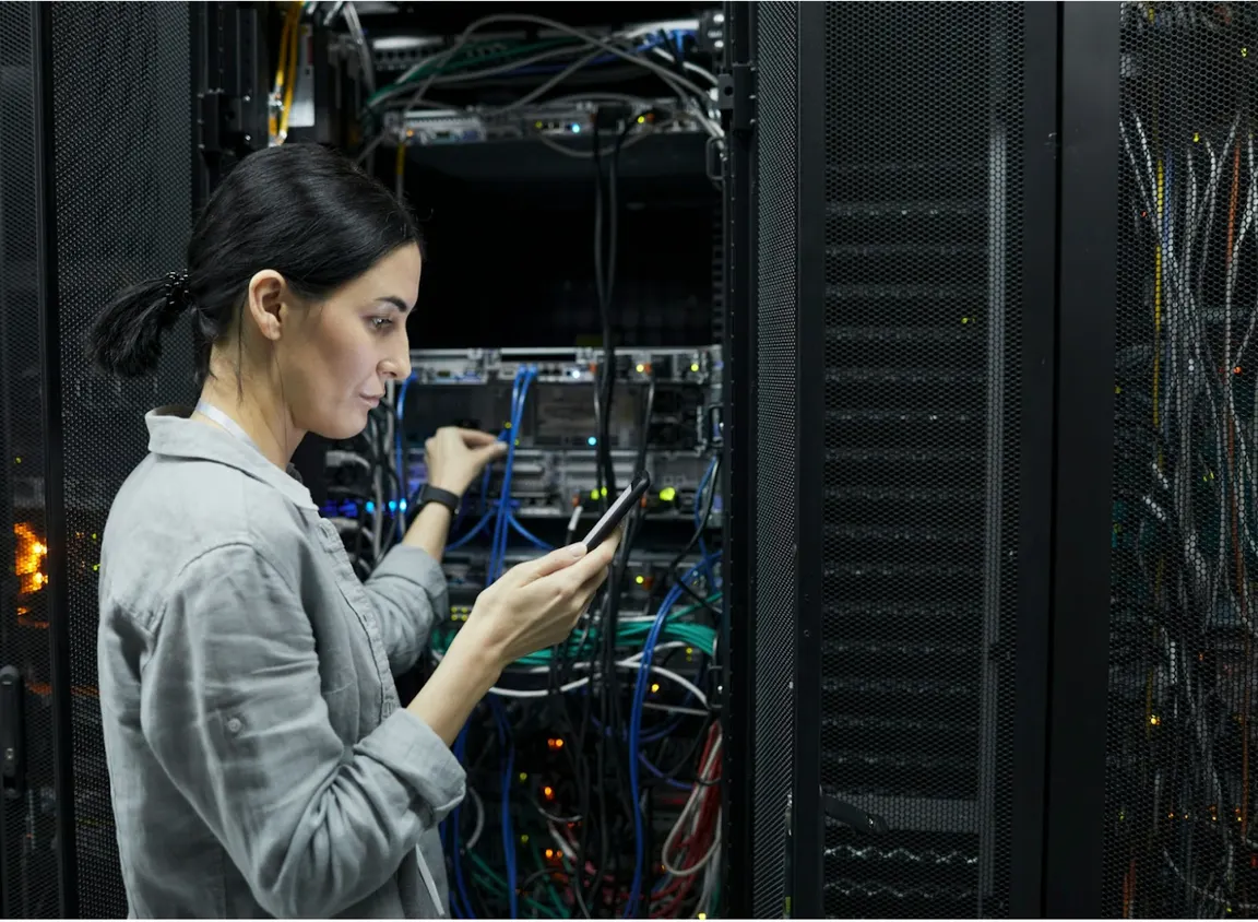 Technician working in a data center managing fiber optic connections, illustrating multimode fiber infrastructure and OM1 vs OM3 network performance in commercial environments