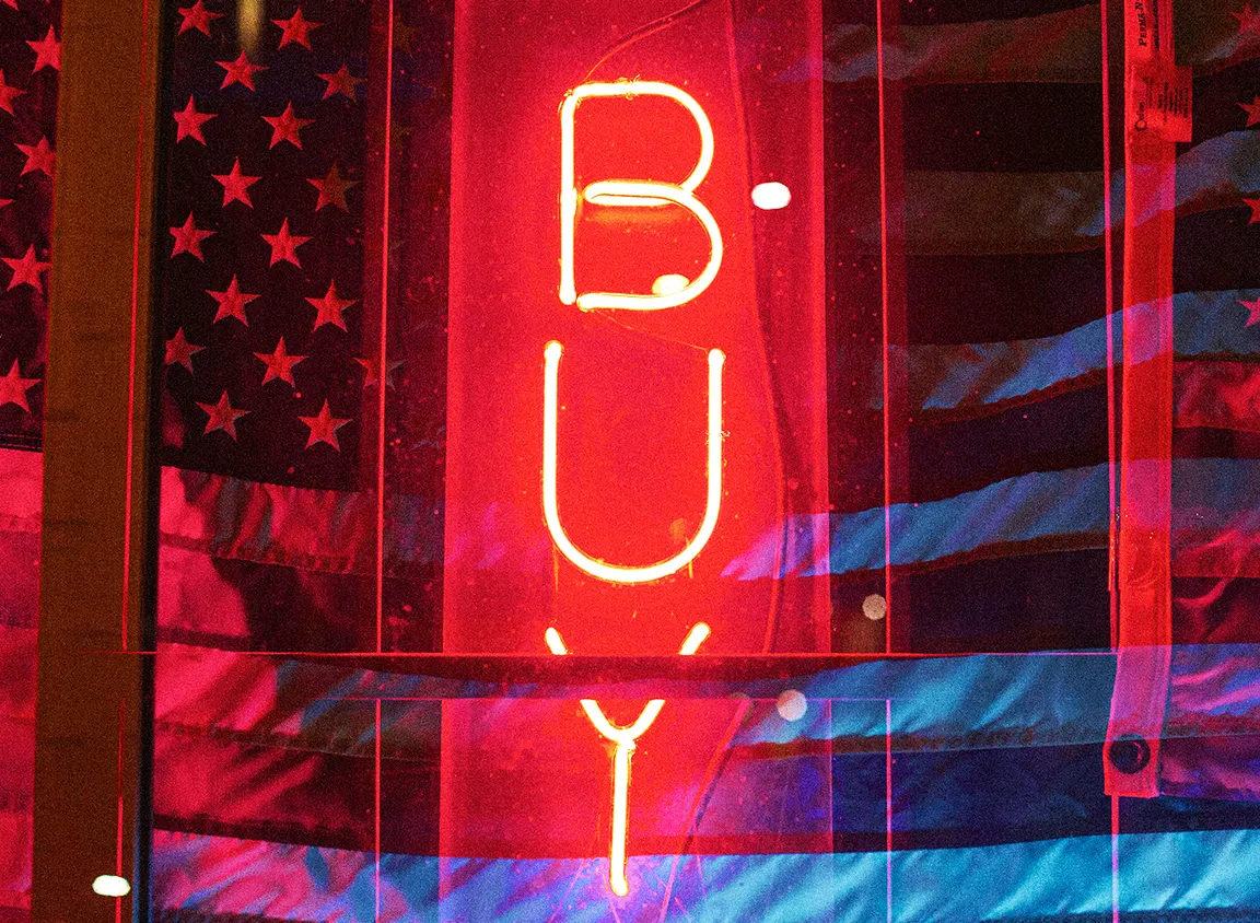 Bold red neon “BUY” sign layered over an American flag, symbolizing Buy American initiatives, domestic manufacturing, and U.S.-made product sourcing.
