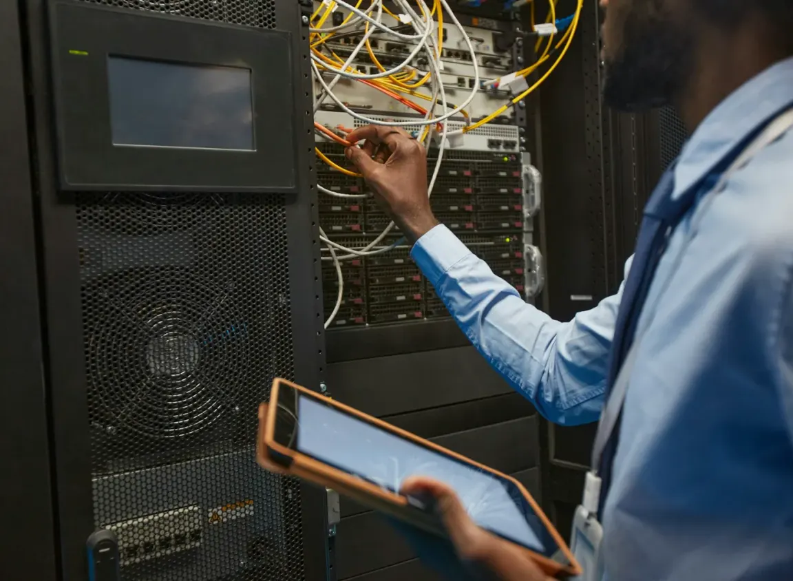 Network technician terminating Ethernet cables inside a commercial server rack using RJ45 wiring standards for structured cabling and reliable network connectivity.
