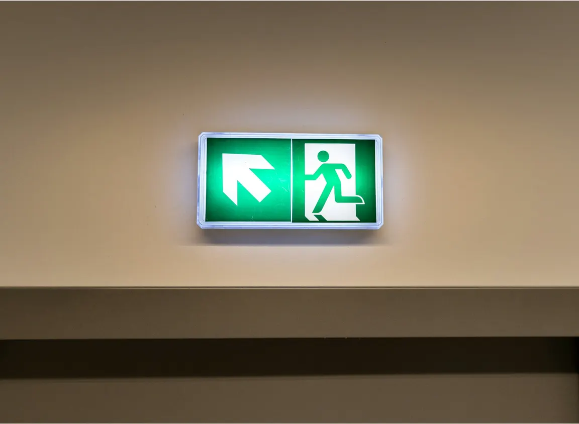 Illuminated emergency exit sign in commercial building, illustrating life safety systems that rely on 2-hour fire rated cable for circuit integrity during emergencies