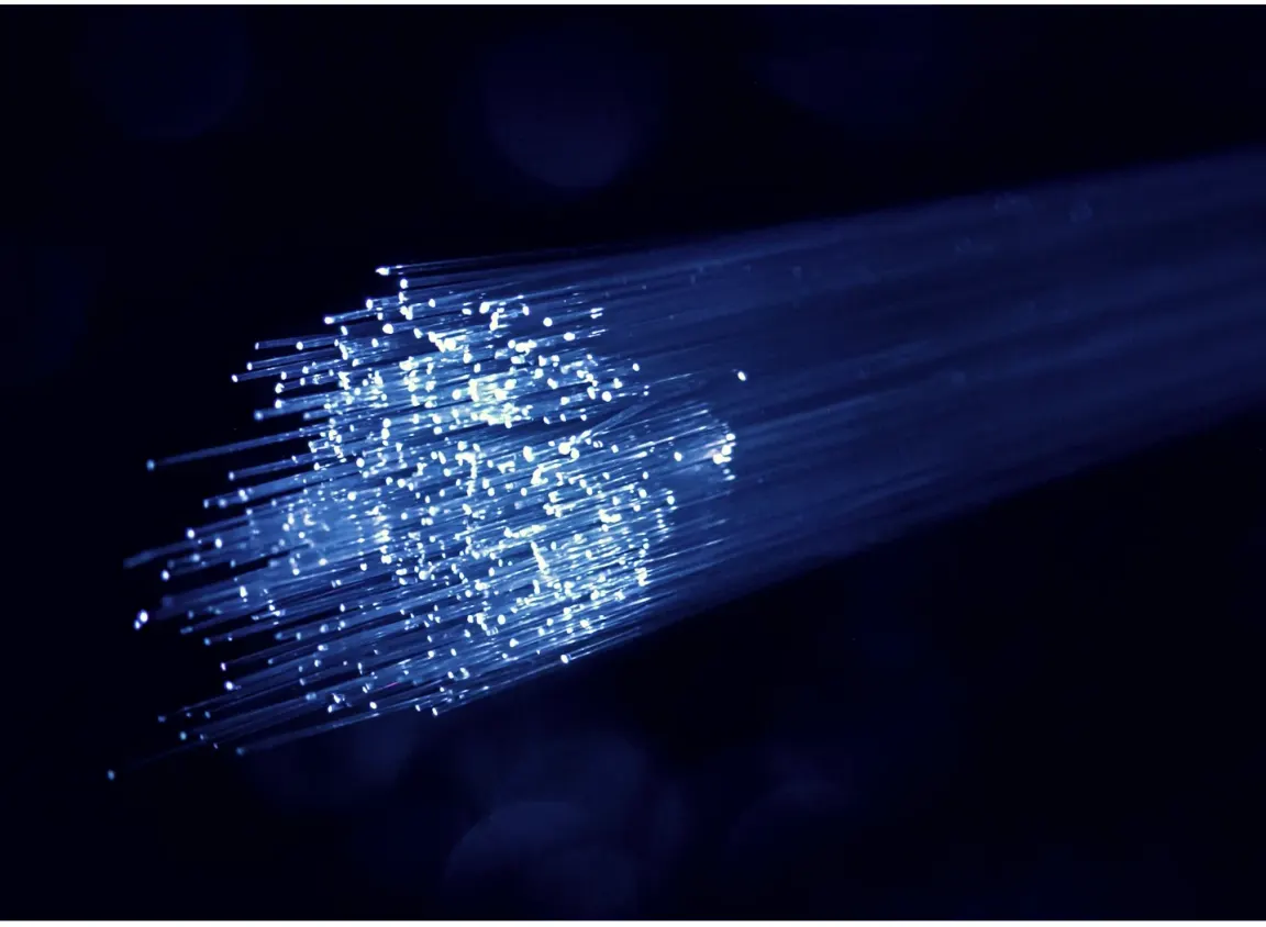 Close-up of illuminated fiber optic strands representing premade fiber optic cable used in enterprise network infrastructure and data transmission