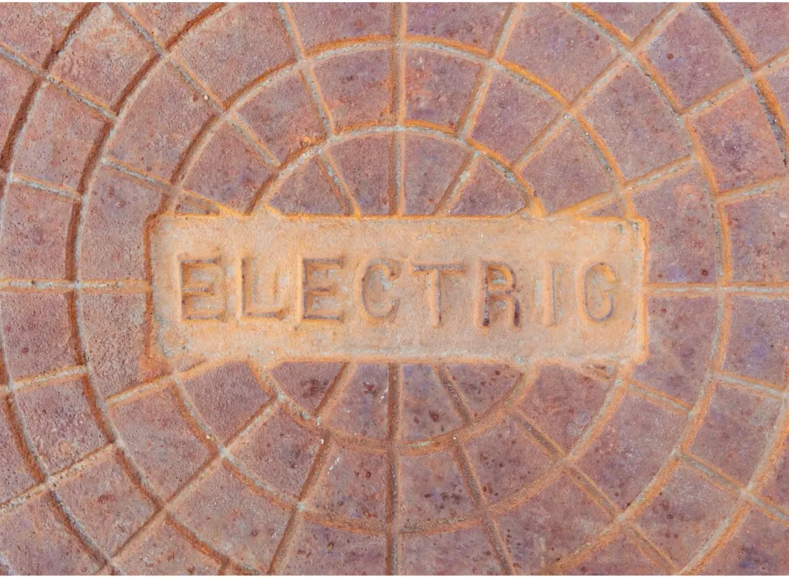Underground electrical access cover representing CATV and outdoor cable infrastructure in commercial utility pathways