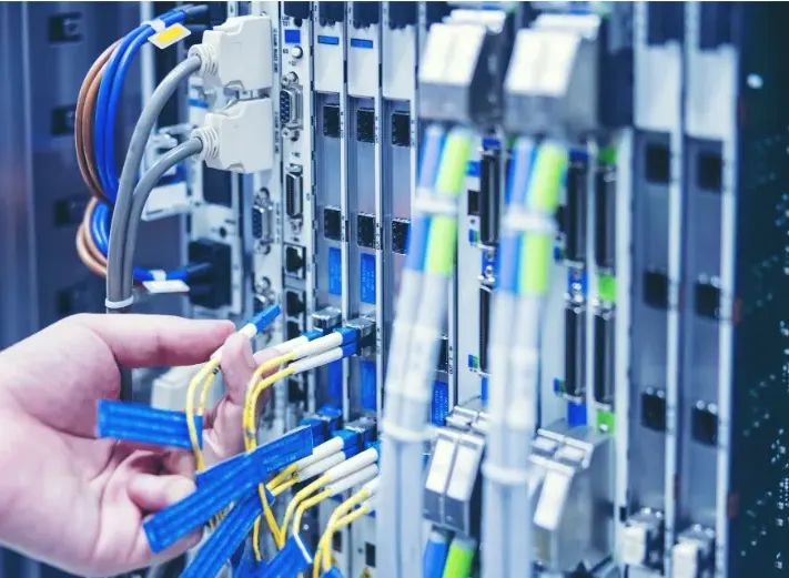 Technician connecting cables in a commercial network equipment rack, the structured cabling environment where choosing the right RJ45 connector affects performance