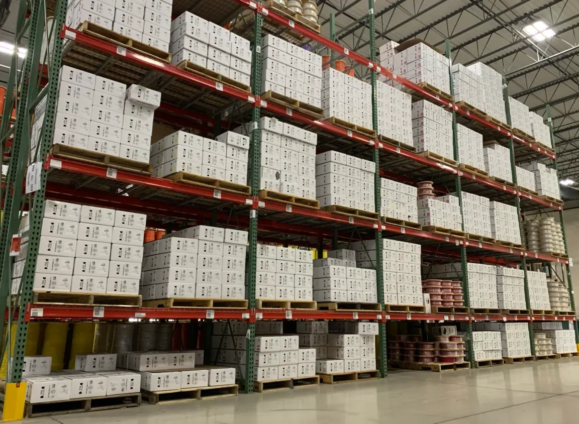 Organized warehouse racks of low‑voltage cable boxes and reels ready for shipment at Windy City Wire.